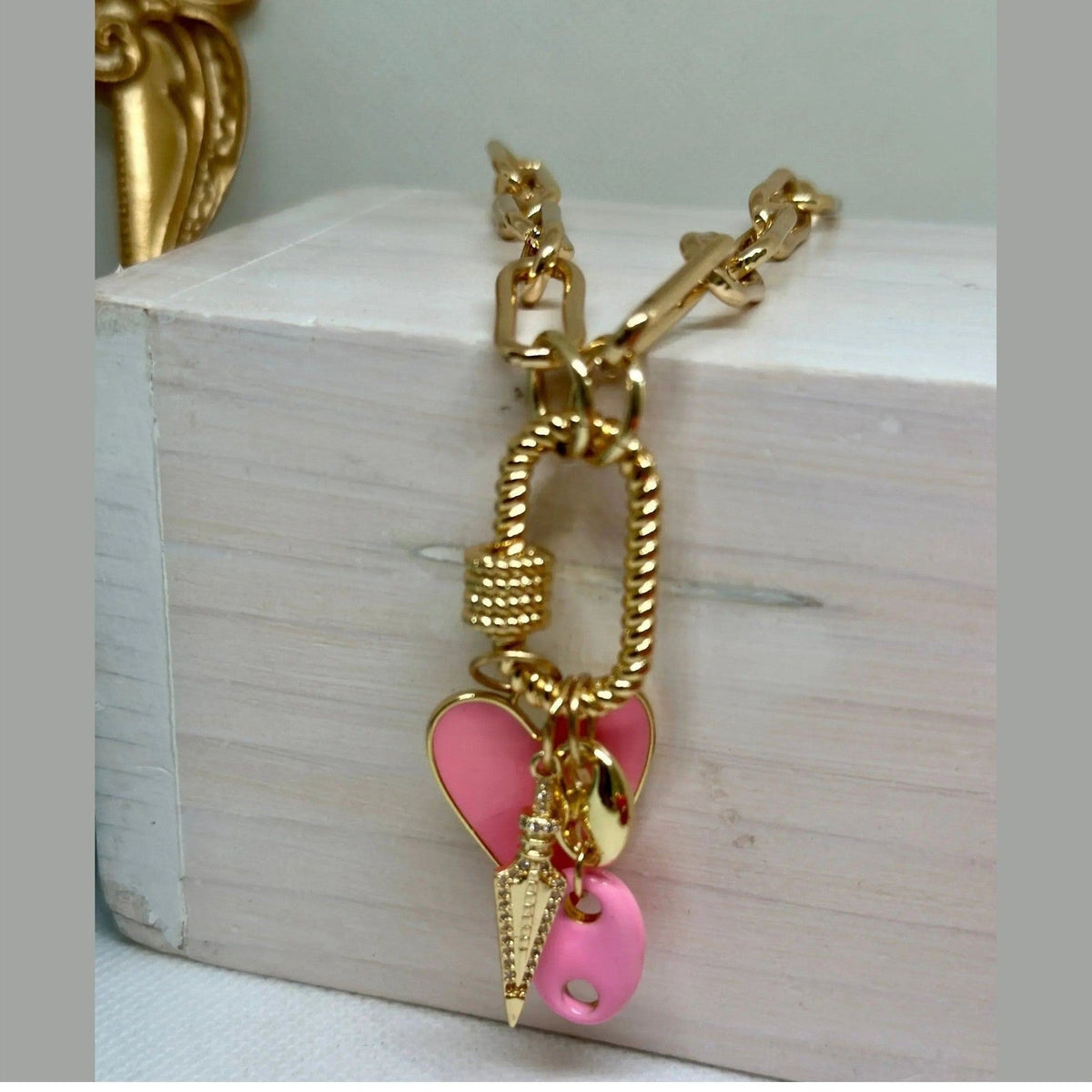 Close-up of Daphne Trio Charms Necklace showing glossy pink heart, textured spike, and oval disc details