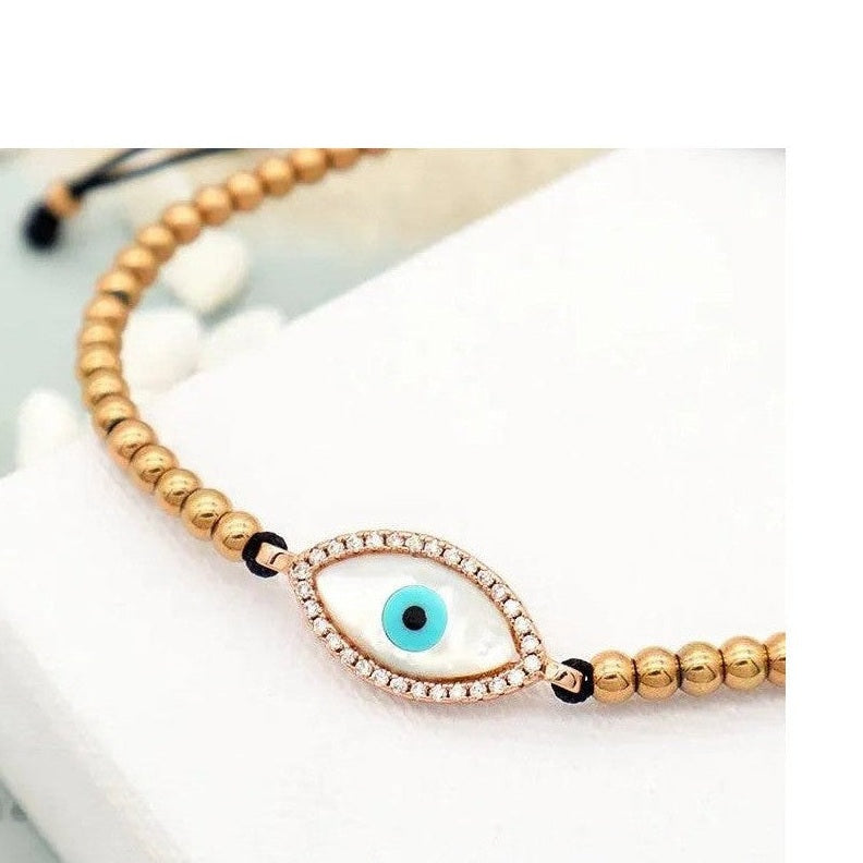 Close-up of gold plated evil eye bracelet with mother-of-pearl surround