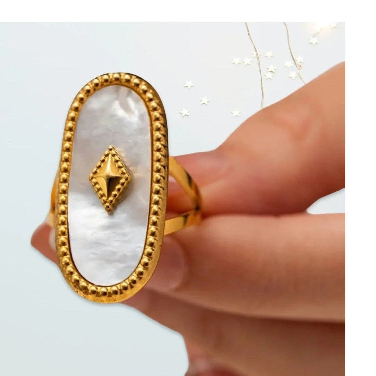Close-up of large oval mother-of-pearl statement ring with gold stud detail