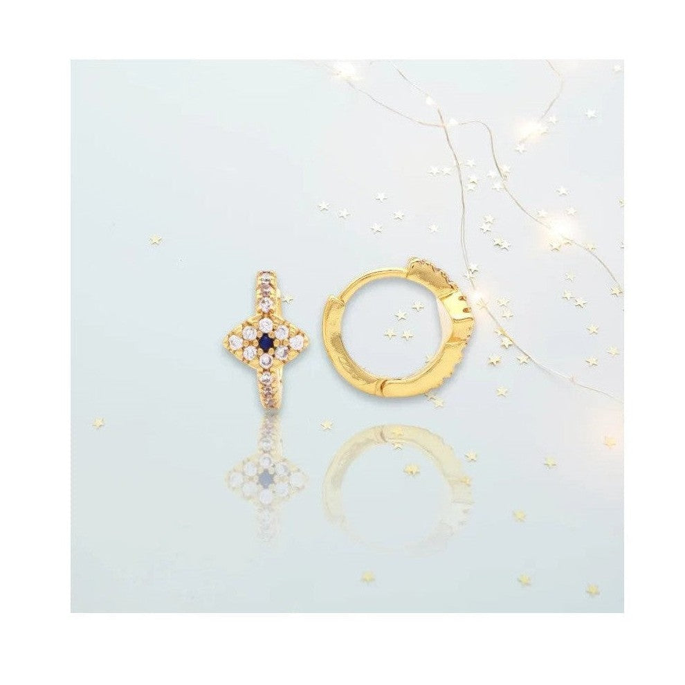 Cross stud with blue gem next to gold huggie hoop